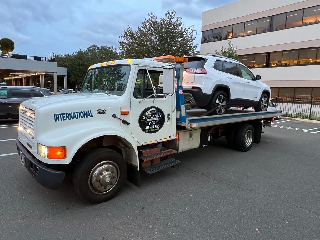 Flatbed tow truck moving a white SUV